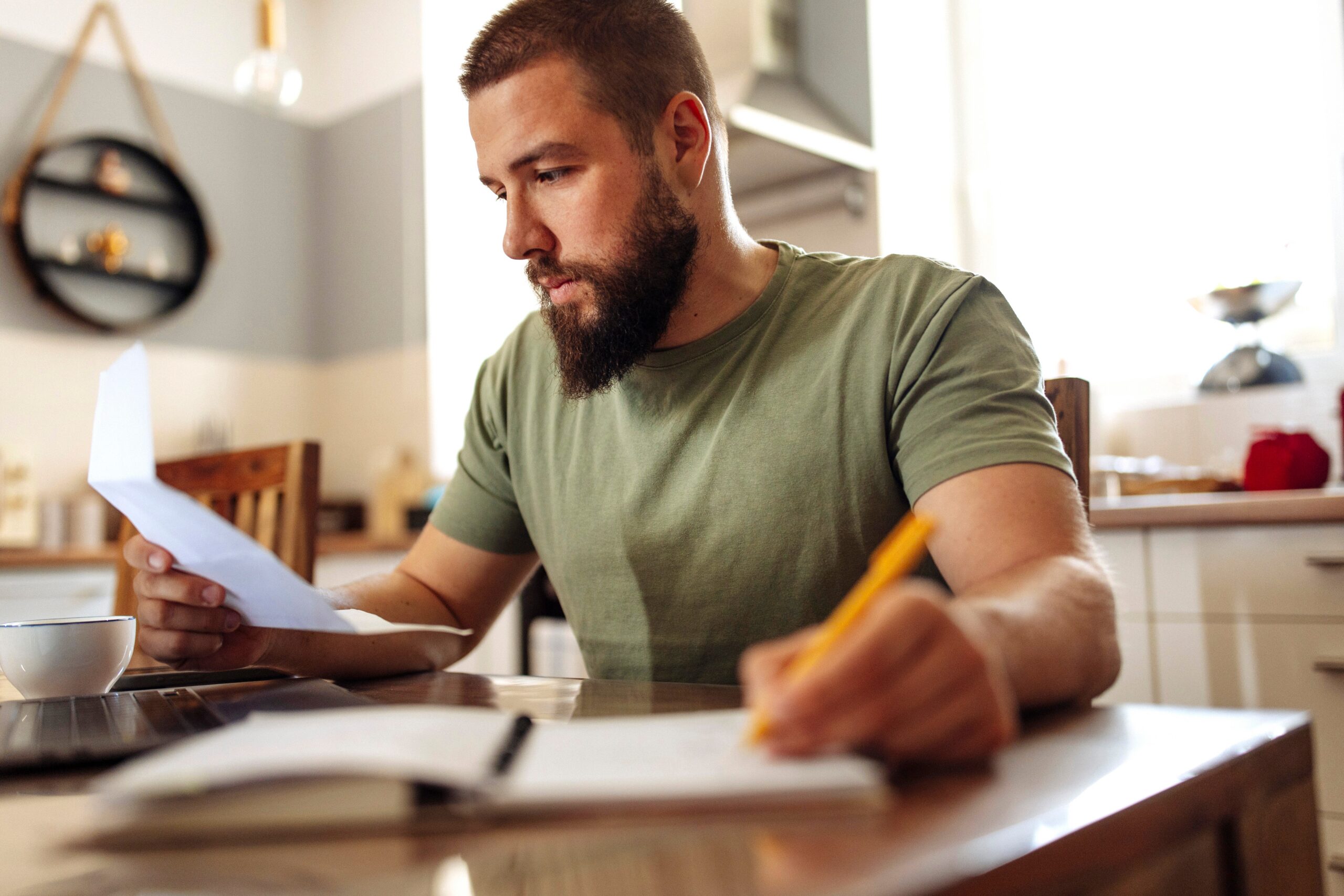 Young adult man with a beard working on finances at home.